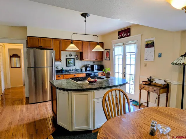 a kitchen with kitchen island a stove a sink a refrigerator and a dining table view