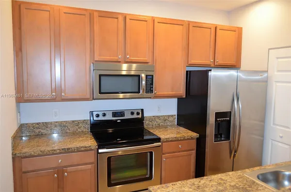 a kitchen with granite countertop a stove microwave and refrigerator