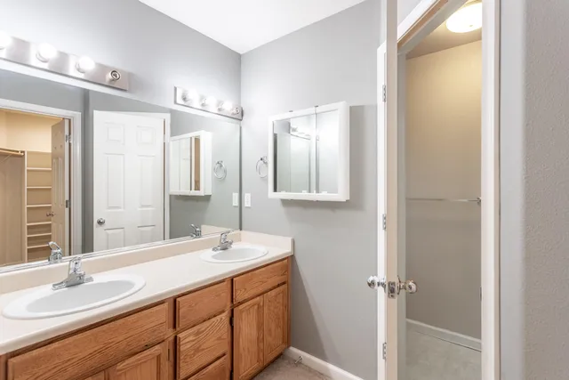 a bathroom with a double vanity sink and mirror with shower