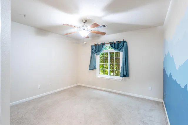 an empty room with windows and fan