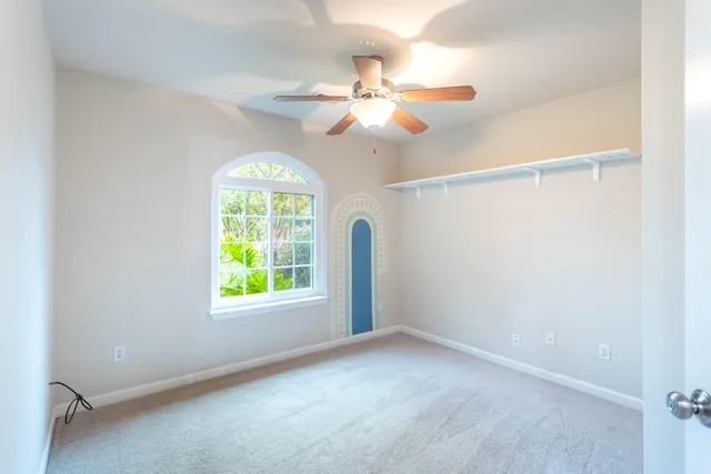 an empty room with windows and fan