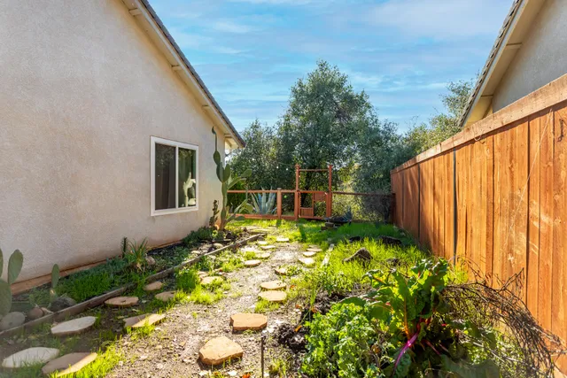 a backyard of a house with table and chairs plants and large trees