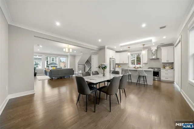 a kitchen with stainless steel appliances a refrigerator a sink dishwasher a stove and white cabinets with wooden floor