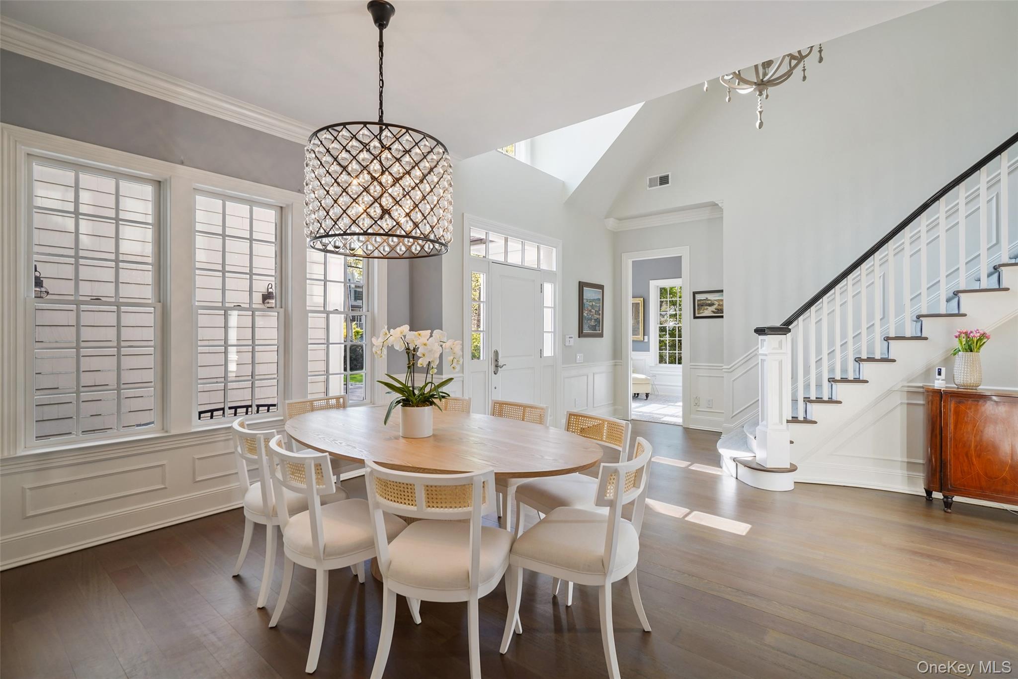 680 Milton Road Rye, NY 10580 - Photo 5 of 32 a dining room with wooden floor a chandelier a glass table and chairs