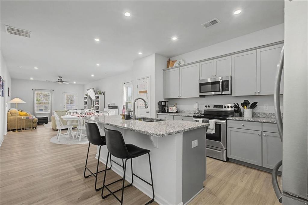 213 Sycamore Drive Calhoun, GA 30701 - Photo 7 of 44 a kitchen with stainless steel appliances kitchen island granite countertop a stove a sink a refrigerator and white cabinets with wooden floor