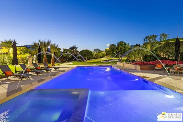 a view of a swimming pool with lawn chairs under an umbrella