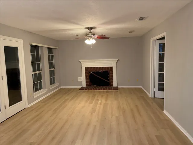 a view of empty room with fireplace and wooden floor