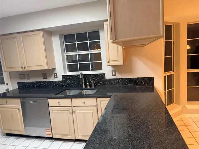 a kitchen with granite countertop a stove a sink and white cabinets