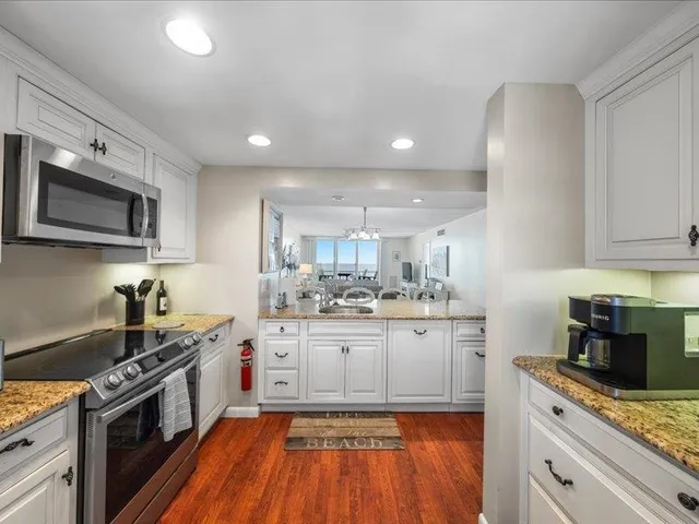 a kitchen with a sink dishwasher and white cabinets with wooden floor