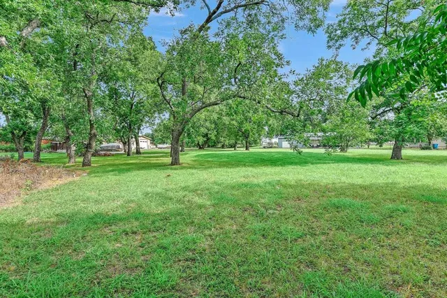 a view of grassy field with benches and trees all around