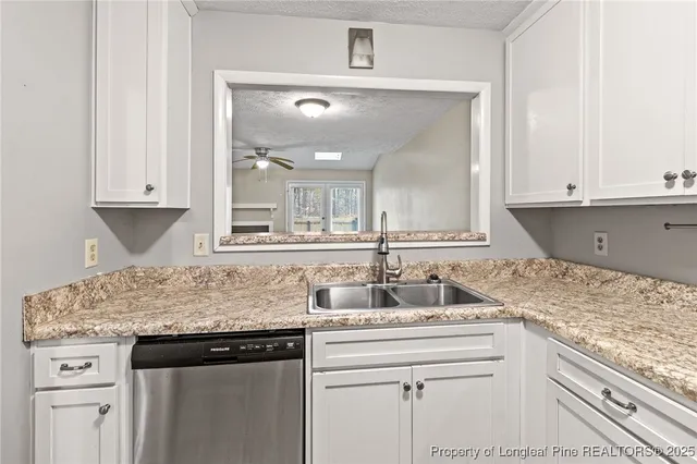 a kitchen with granite countertop white cabinets and stainless steel appliances
