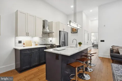 a kitchen with stainless steel appliances kitchen island a table chairs in it and wooden floors