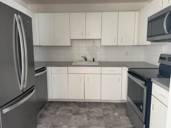 a kitchen with white cabinets and stainless steel appliances