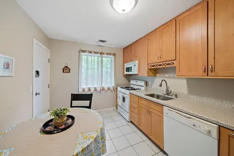 a kitchen with stainless steel appliances a sink a stove a refrigerator white cabinets and a window