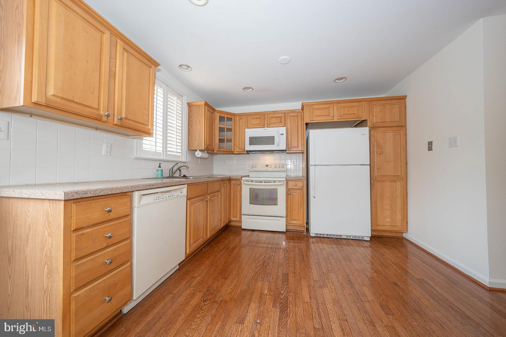 231 Plant Avenue Wayne, PA 19087 - Photo 6 of 35 a kitchen with granite countertop wooden floors and white stainless steel appliances