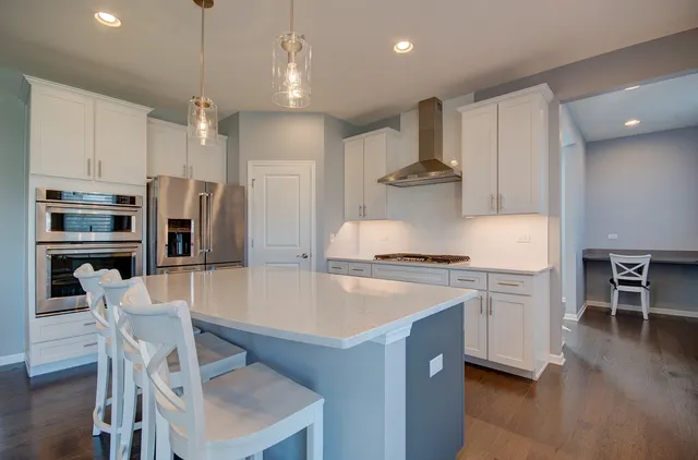 a large kitchen with stainless steel appliances a stove a sink a refrigerator and chairs