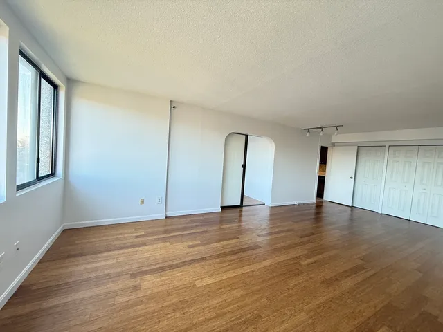 a view of an empty room with window and wooden floor
