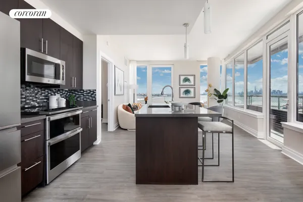 a living room with stainless steel appliances kitchen island granite countertop a stove and a sink