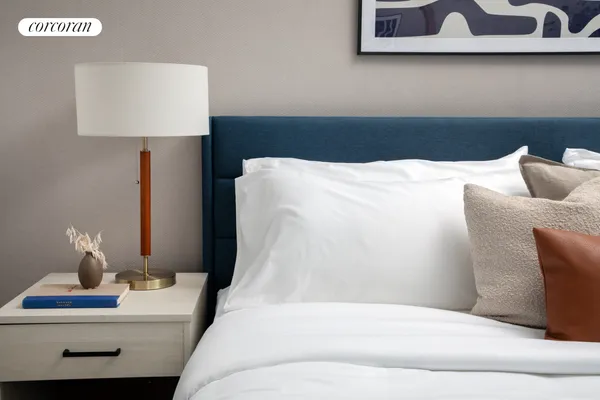 a bedroom with a bed and a lamp on dresser