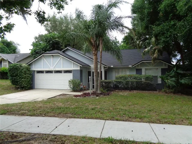 a view of a house with a yard and large trees