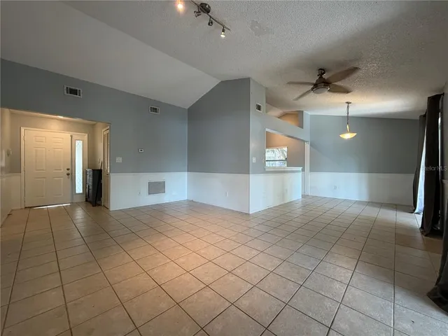 wooden floor with a chandelier fan and kitchen view