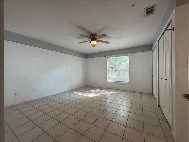 an empty room with windows and fan