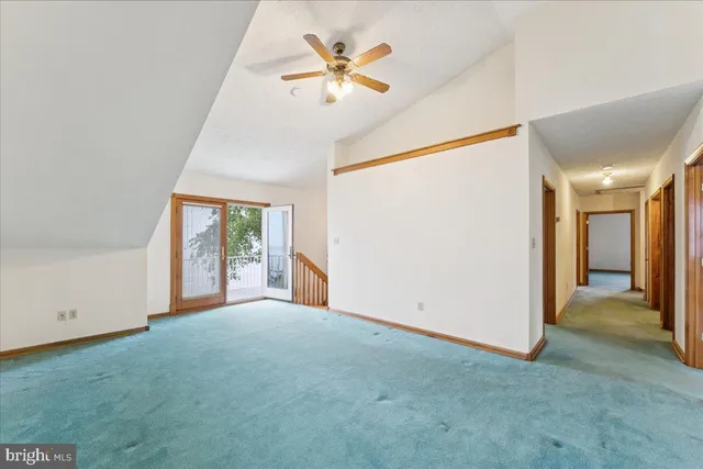 an empty room with chandelier fan and windows