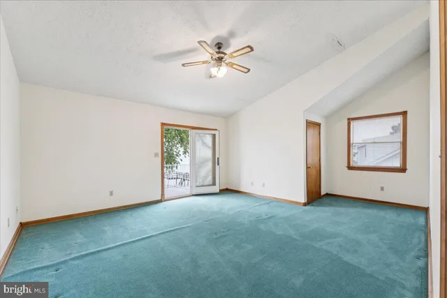 a view of an empty room with chandelier fan and closet area