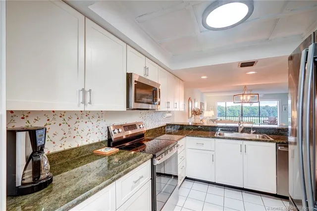 a kitchen with granite countertop a sink a stove and cabinets