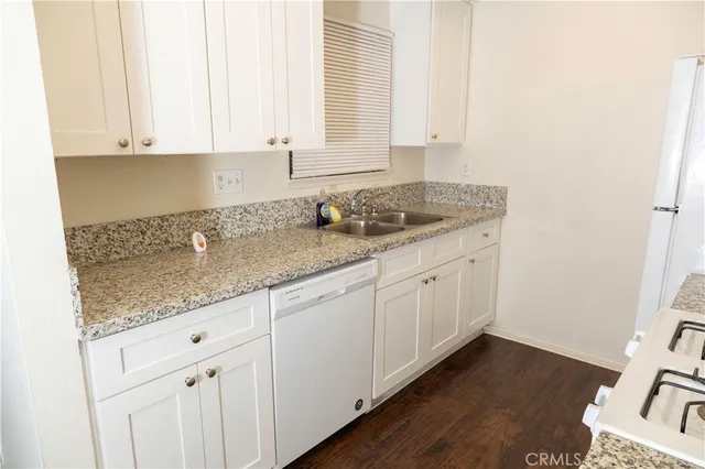 a kitchen with granite countertop white cabinets and a sink