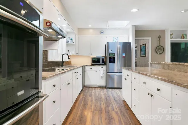 a large kitchen with stainless steel appliances kitchen island granite countertop a stove and a sink