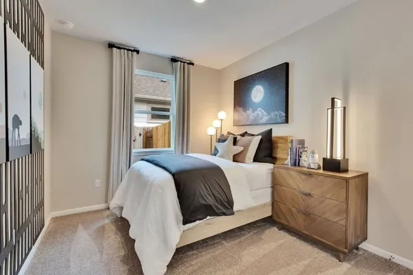 a bedroom with a bed and a lamp on dresser