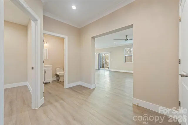 a view of a hallway with wooden floor and a bathroom