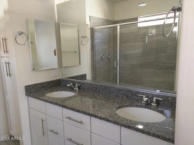 a bathroom with a granite countertop double vanity sink and a mirror
