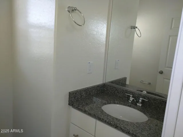 a bathroom with a granite countertop toilet sink and mirror