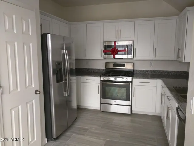 a kitchen with stainless steel appliances a refrigerator stove and white cabinets