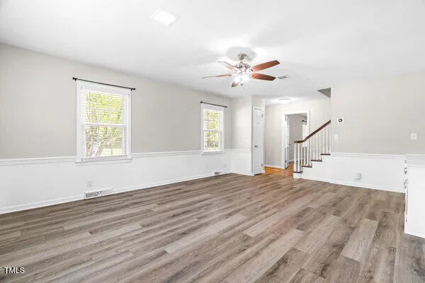 a view of empty room with wooden floor and ceiling fan