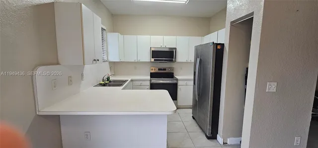 a kitchen with a refrigerator a stove top oven a sink and cabinets