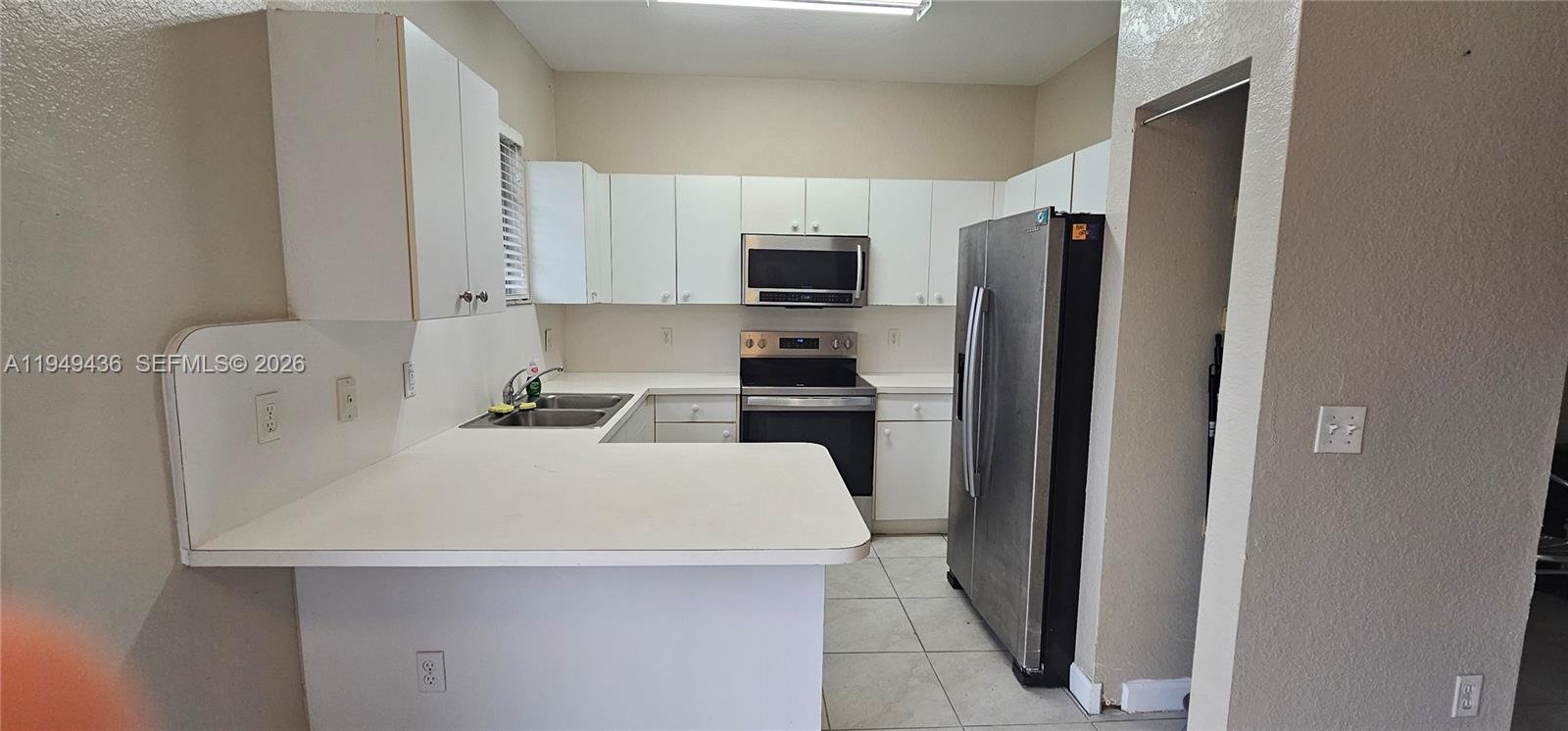 2711 Northeast 4th Street, Unit 204 Homestead, FL 33033 - Photo 4 of 13 a kitchen with a refrigerator a stove top oven a sink and cabinets