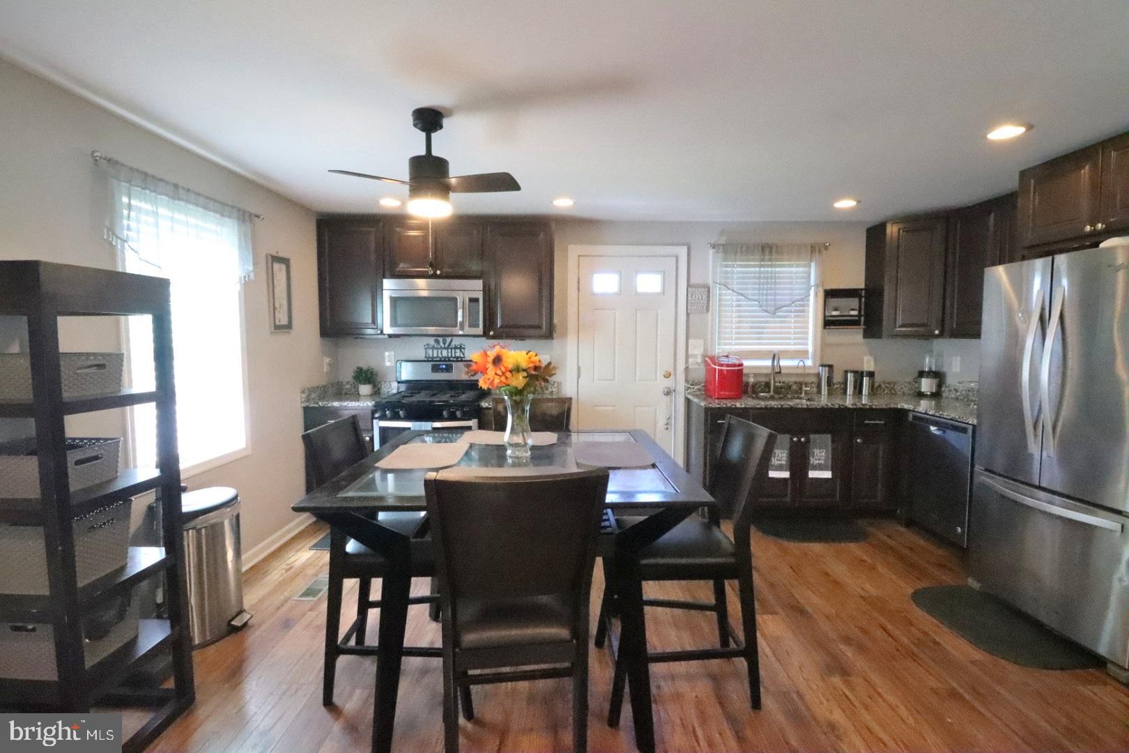 718 Cliffedge Road Pikesville, MD 21208 - Photo 8 of 28 a kitchen with stainless steel appliances a dining table chairs refrigerator and cabinets