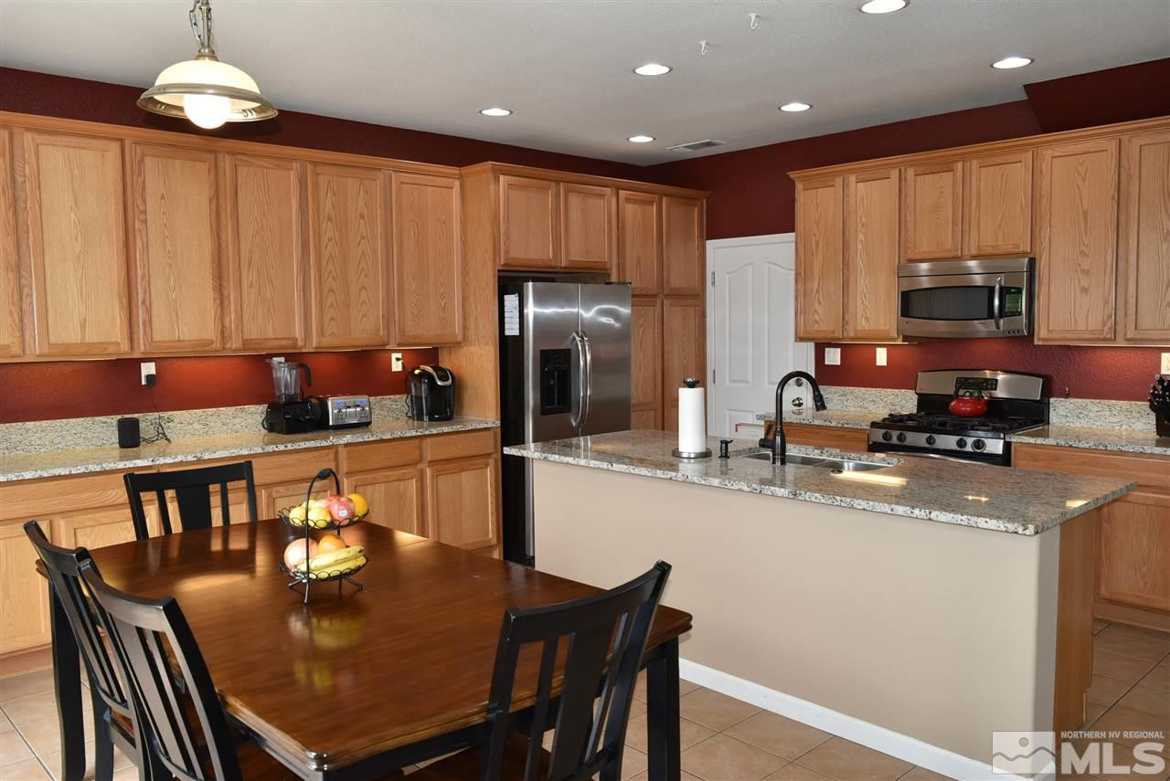 10675 Cedar Bend Court Reno, NV 89521 - Photo 5 of 22 a kitchen with stainless steel appliances granite countertop a stove a refrigerator a kitchen island a table and chairs