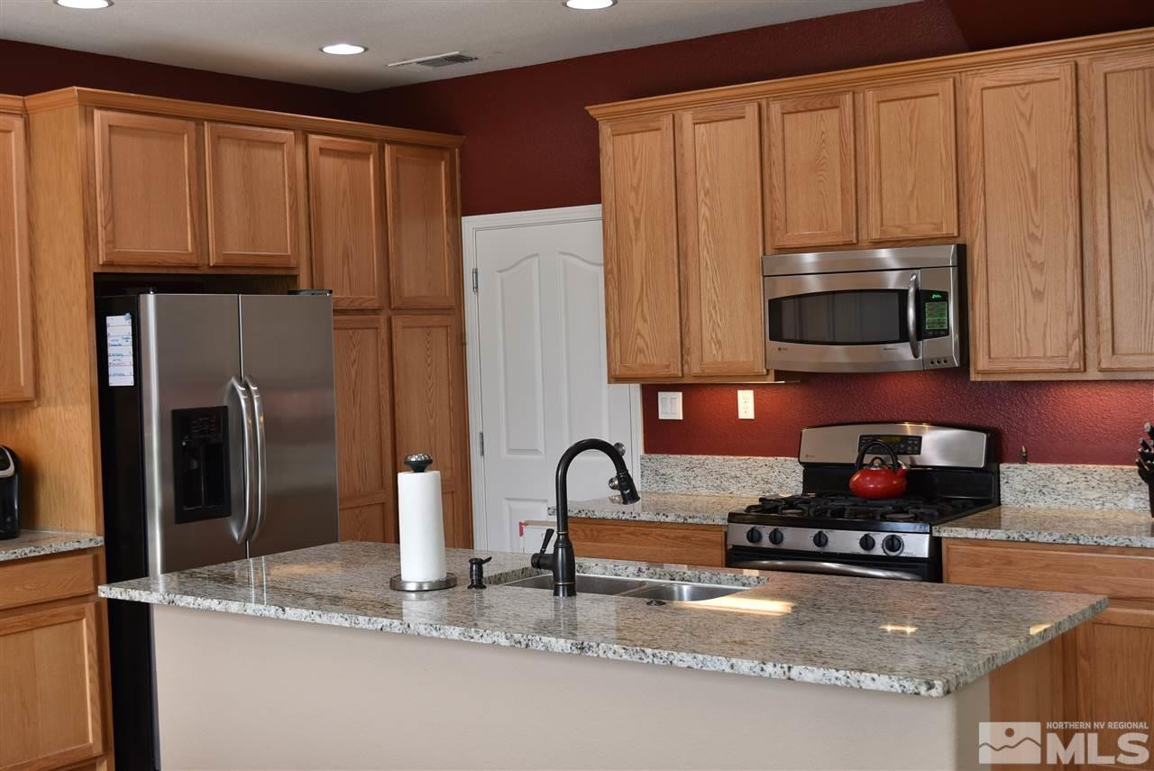 10675 Cedar Bend Court Reno, NV 89521 - Photo 7 of 22 a kitchen with granite countertop a refrigerator and a stove top oven