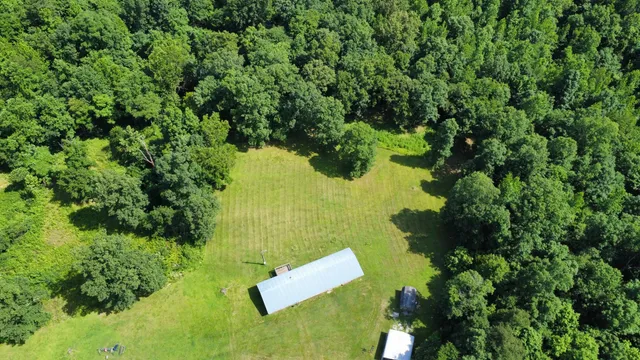 an aerial view of residential house with outdoor space and trees all around