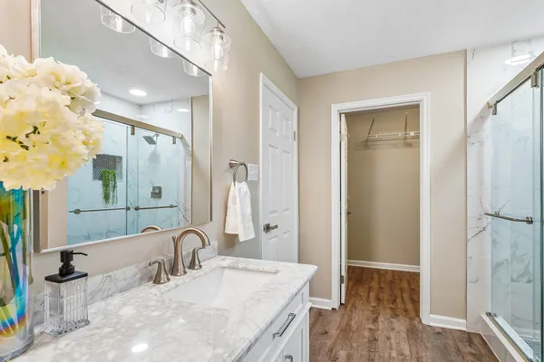 a bathroom with a granite countertop sink a mirror and shower