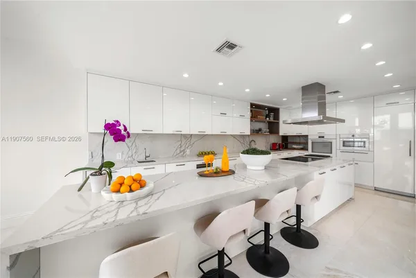 a kitchen with stainless steel appliances kitchen island granite countertop a sink and a refrigerator
