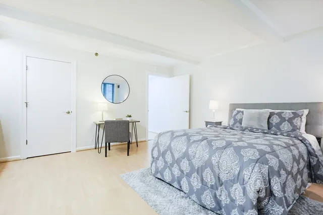 a bedroom with a bed a table and a potted plant