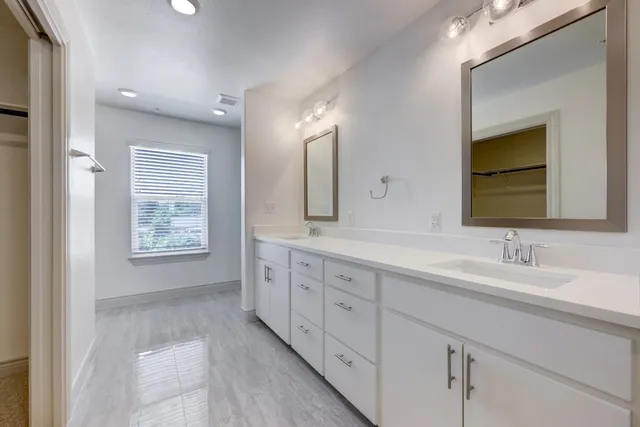 a bathroom with double vanity two mirror and a bathtub