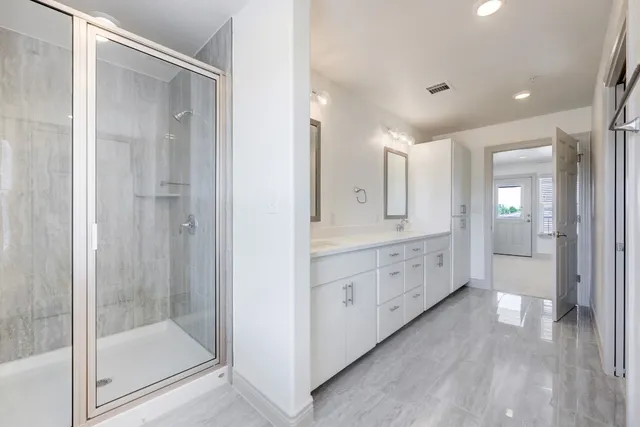a bathroom with a glass door shower a sink and a mirror