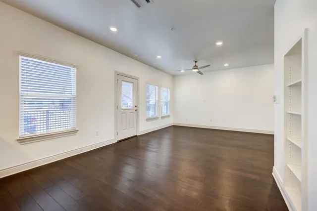 an empty room with wooden floor and windows