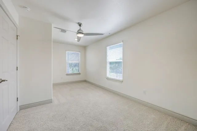 an empty room with a ceiling fan and windows
